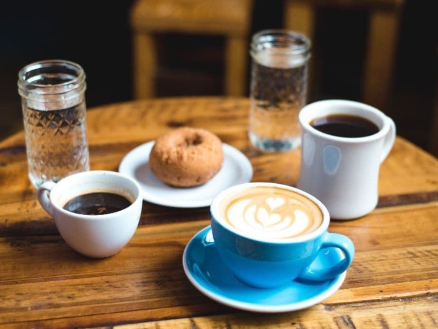 木製テーブルにのったカフェオレとドーナツ