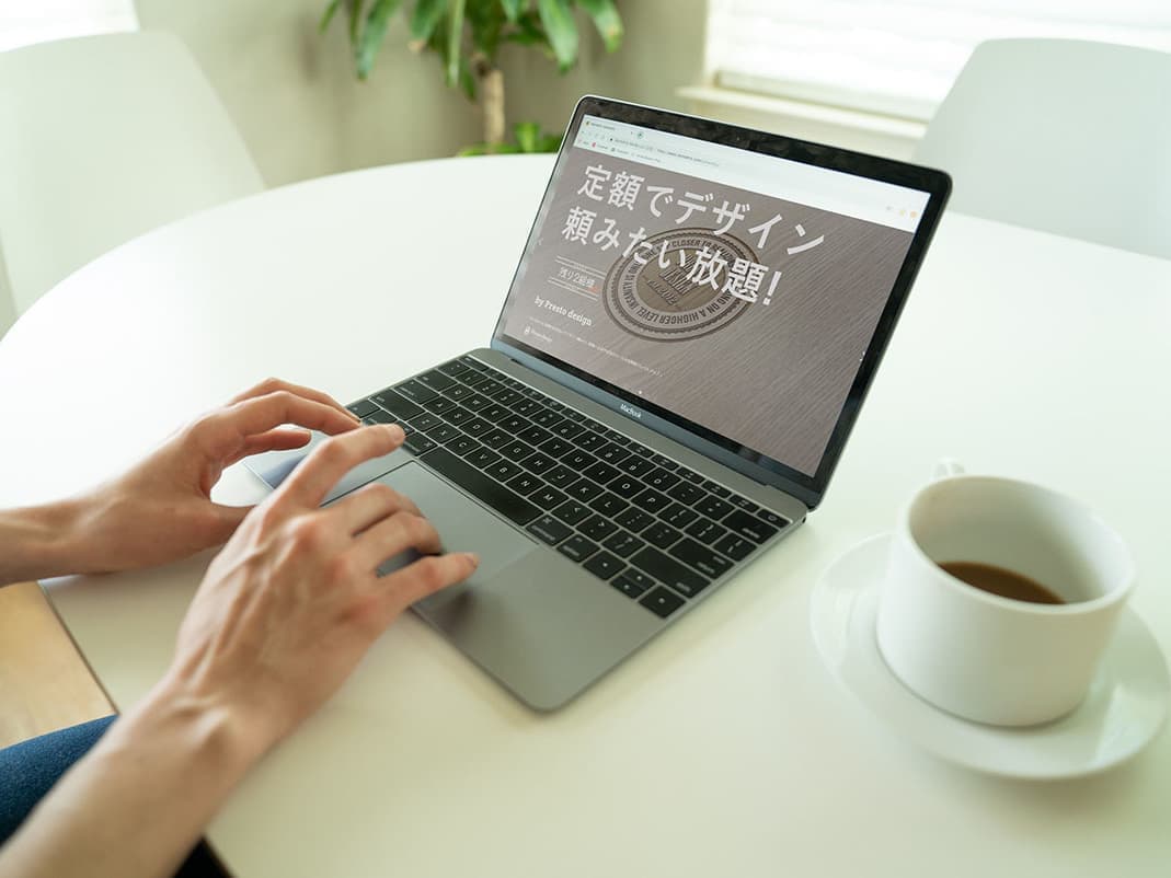 白いテーブルにのったノートパソコンを操作する女性の手